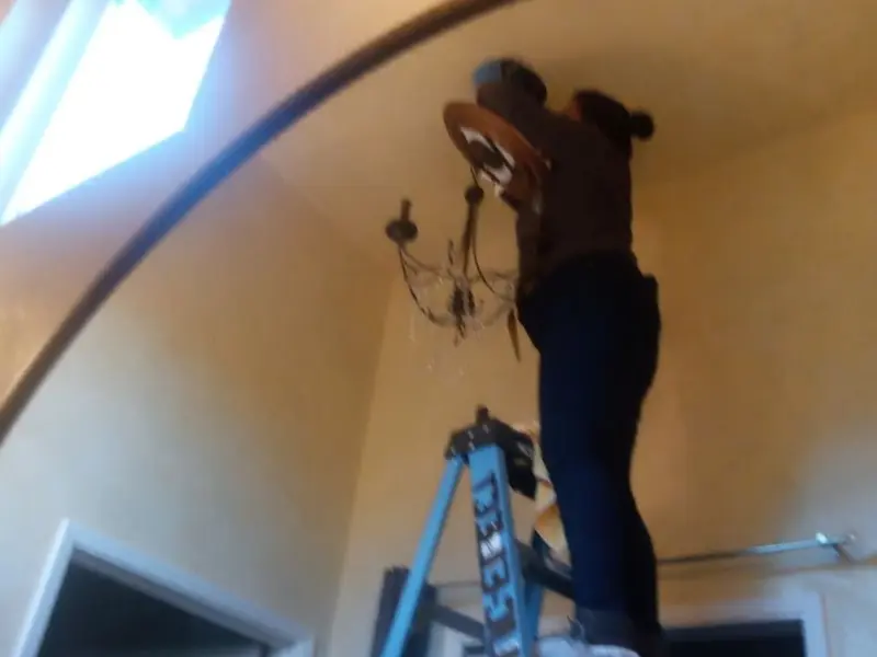Electrician installing a chandelier in a Pomona residence